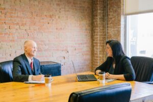 An elderly man discussing funeral plans with a professional, who is using a laptop to review and explain prepaid funeral options and details