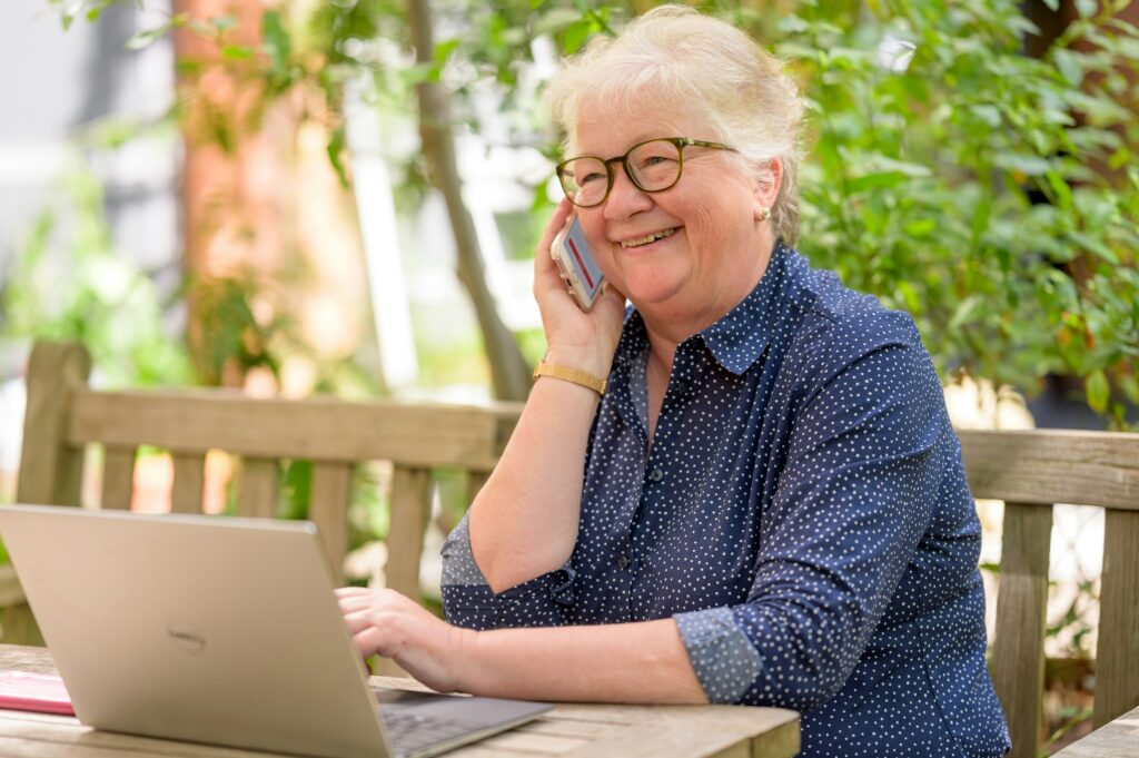 Elderly woman making a phone call to inquire about burial insurance options, focusing on securing immediate coverage.