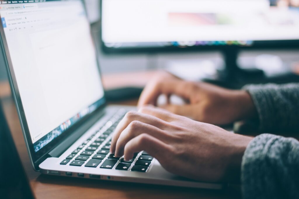 Close-up of a hand using a laptop to manage custom funeral planning.