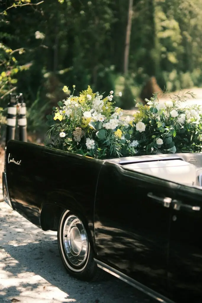 A somber black vehicle adorned with flowers, part of a funeral procession