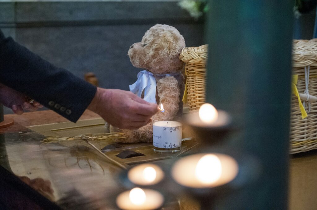 Soft, cuddly teddy bear placed as a sentimental tribute at a memorial service.