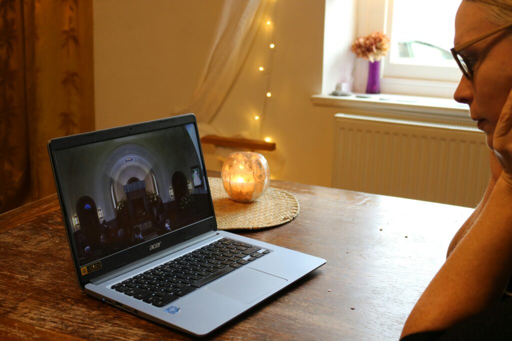 Virtual funeral setup on a computer screen with a photo of the deceased displayed and participants attending remotely.